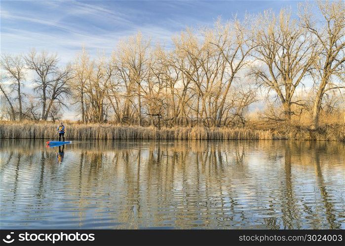 Paddling stand up paddleboard on a calm lake, early spring scenery in northern Colorado