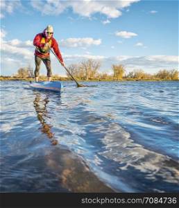 paddling stand up paddleboard on lake in Colorado, fall scenery with wind