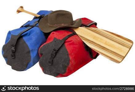 paddling trip or vacation concept - wooden canoe paddle, waterproof duffels dity by river mud and hat isolated on white