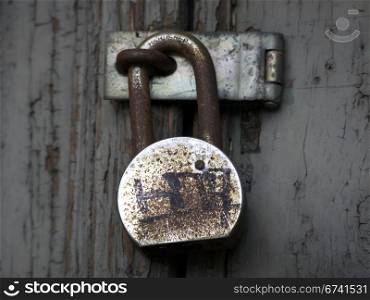 Padlock with graffiti. Old rusty padlock on wooden door