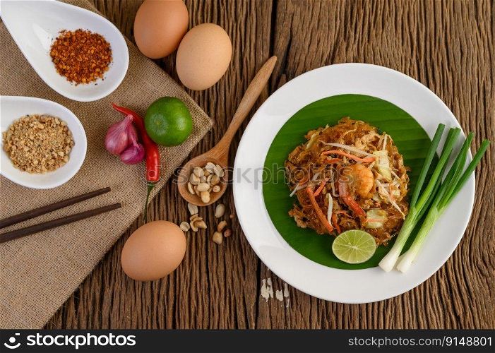 Padthai shrimp in a black bowl with eggs, Spring onion, and Seasoning on wooden table.