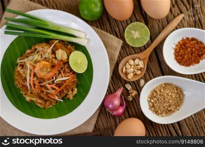 Padthai shrimp in a black bowl with eggs, Spring onion, and Seasoning on wooden table.