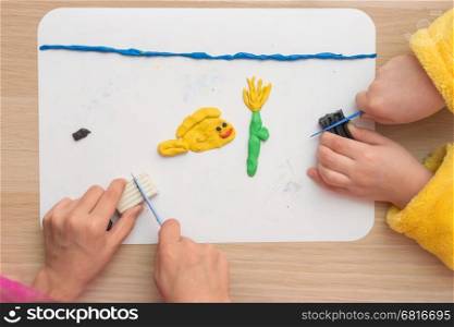 Page Online Two children are molded from clay on board fish and underwater flower in the sea, the top view