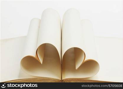 Pages of open book rolled in heart shape isolated on white