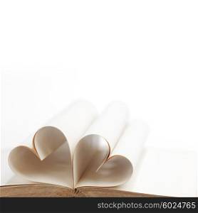 Pages of open book rolled in heart shape isolated on white