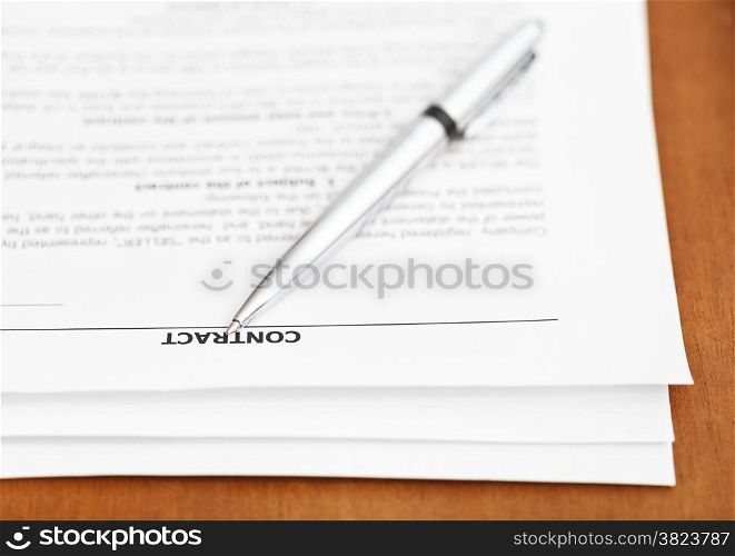 pages of sales contract and silver pen close up on wooden table