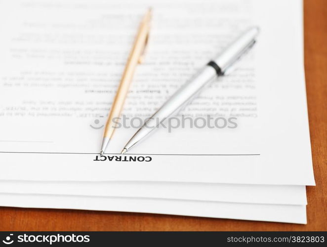 pages of sales contract and two pens close up on wooden table