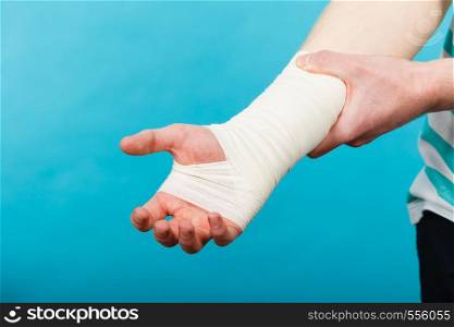 Pain and injury concept. Young man holds bandaged hand. Injured part of body. Medicine and healthcare.. Man with painful bandaged hand.