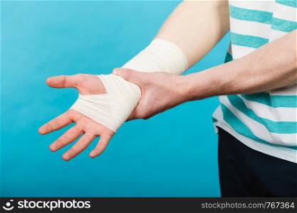 Pain and injury concept. Young man holds bandaged hand. Injured part of body. Medicine and healthcare.. Man with painful bandaged hand.