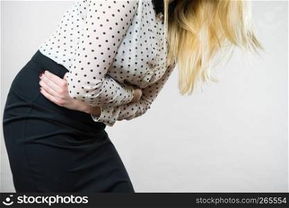 Painful periods and menstrual cramp problems concept. Woman having stomach cramps feeling very unwell.. Woman feeling stomach cramps holding her belly