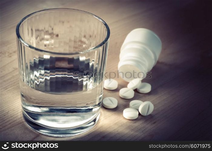 Painkiller. Abstract medical backgrounds with pills and glass of water over wooden desk