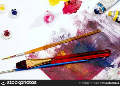 Paint and brushes set aside on a table work space.