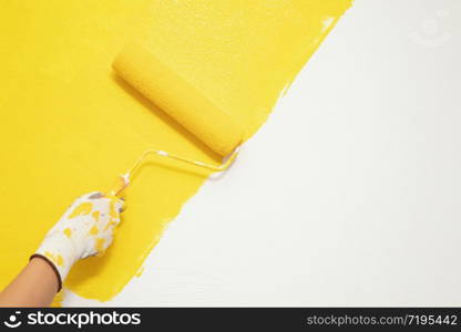 Paint brush, close up hand painter worker painting on surface wall Painting apartment, renovating with yellow color paint. Leave empty copy space to write descriptive text beside.