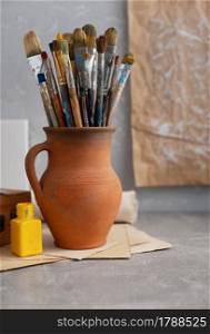Paint brush in clay jug and art painter tool on table background texture. Paintbrush for painting as artistic paint still life. Abstract art concept
