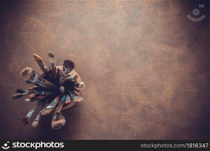 Paint brush in clay jug at art painting canvas as abstract background texture. Paintbrush for painting for artistic paint still life. Abstract art concept