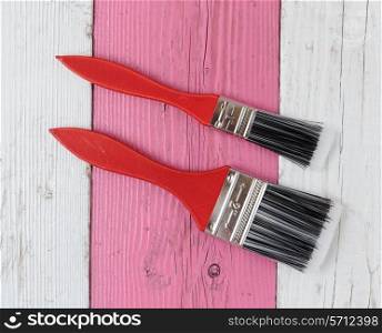 Paint brush on a white and pink wooden board