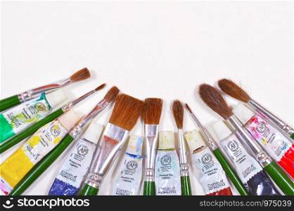 Paint brushes and used color tubes isolated on a cream background