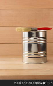 paint bucket and paintbrush on wooden background