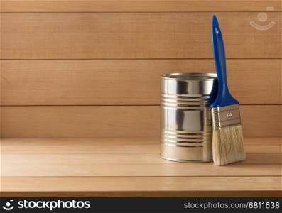 paint bucket and paintbrush on wooden background