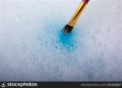 Paint dissolving in water as painting brush touching water