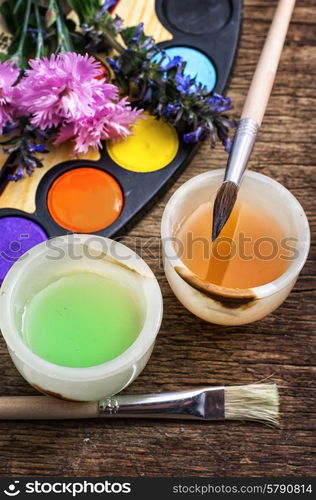 paint for drawing. palette of colors for painting and brushes on wooden vintage background.