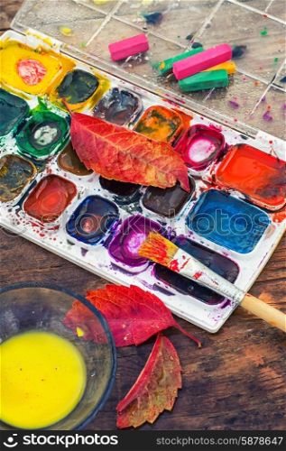 Paint on the autumn table. set of different paint colors and brush for painting on wooden background in the autumn style