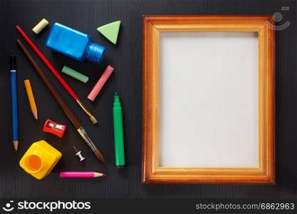 paint supplies and frame on black wooden background
