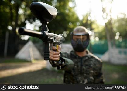 Paintball player aimimg with gun on playground. Extreme sport with pneumatic weapon and paint bullets or markers, military game outdoors, combat tactics. Paintball player aimimg with gun on playground