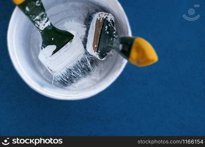 Paintbrush in paint can on blue background