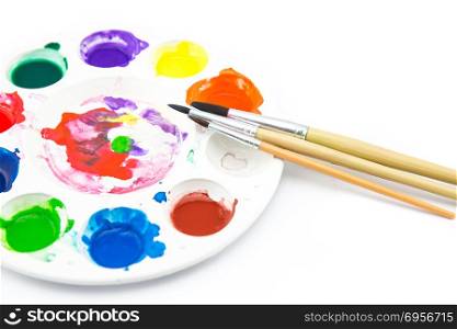 paintbrush lies on the palette with paints on white background