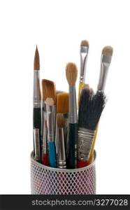 Paintbrushes in a metal mesh holder on white background.