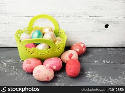 Painted Easter Eggs in decorated green basket on wooden table. Holiday background