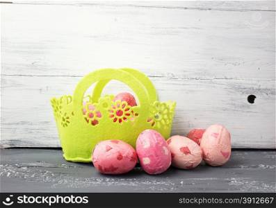 Painted Easter Eggs in decorated green basket on wooden table. Holiday background