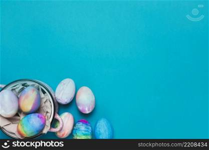 painted easter eggs inside cooking pot blue backdrop with copy space writing text