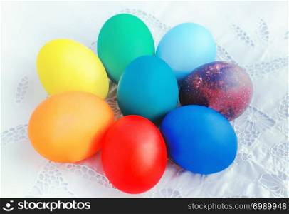 Painted in the colors of the rainbow Easter eggs in the form of a flower on a white vintage tablecloth. Selective focus.. Colorful Easter Eggs