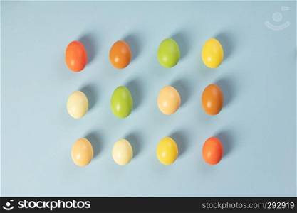 Painted traditional eggs for Easter holiday over light blue background, top view, copy space