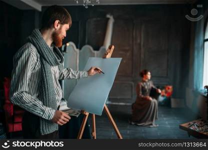 Painter drawing female portrait against easel in art studio. Oil paint