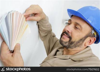 painter in blue hat holding color swatches