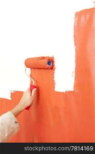 Painter painting over a white wall, making it bright organge with a paint roller