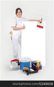 Painter posing with her supplies next to a blank sign