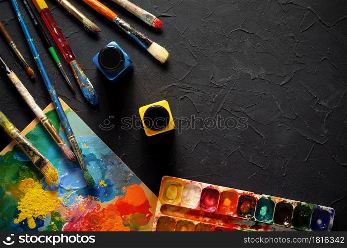 Painter tool and paint brush at black abstract background texture. Paintbrush and palette for oil painting still life. Art concept