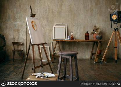 Painter tools and easel in art studio, nobody. Creative artist equipment, workplace. Atelier or workshop interior. Painter tools and easel in art studio, nobody