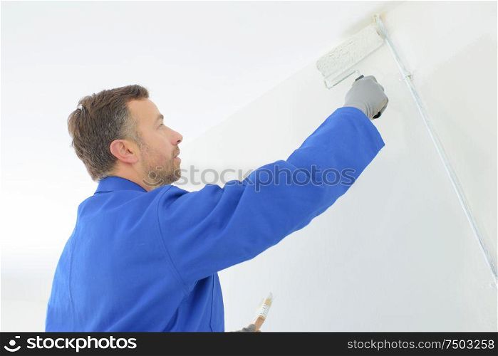 painter using roller to repaint interior wall