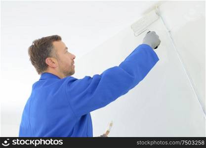 painter using roller to repaint interior wall