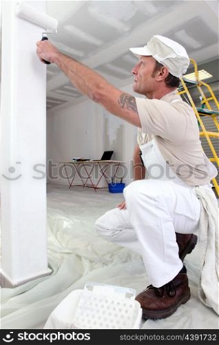 Painter with roller kneeling down