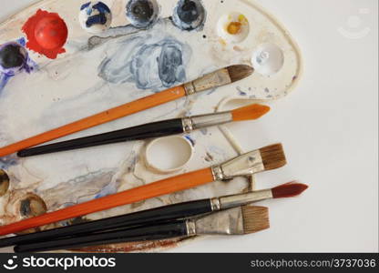 Painting brushes and artistic color palette on white paper