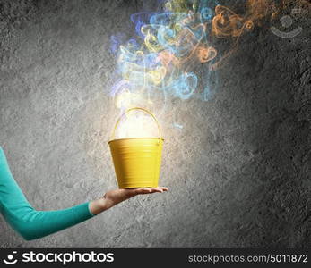 Painting concept. Close up of female hand holding bucket with colorful fumes