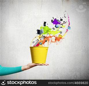 Painting concept. Close up of female hand holding bucket with colorful splashes