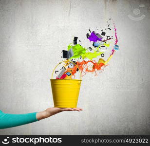 Painting concept. Close up of female hand holding bucket with colorful splashes