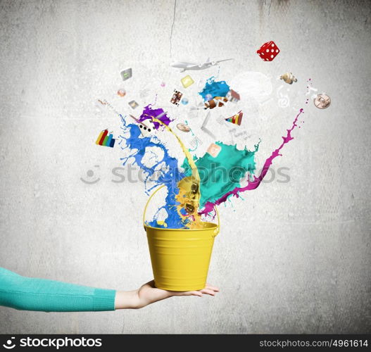 Painting concept. Close up of female hand holding bucket with colorful splashes